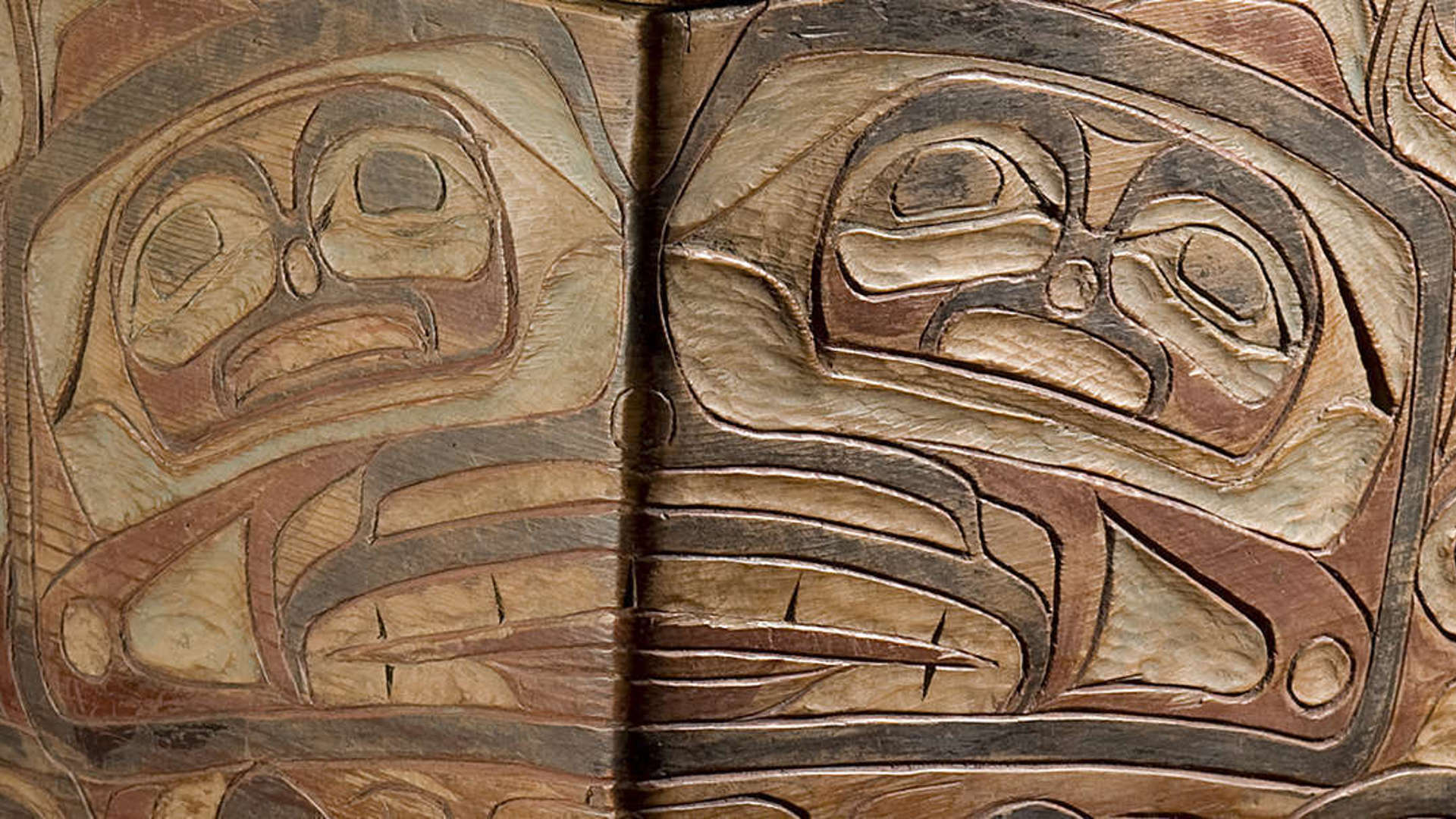 Close up of a Northwest Coast Native American carved wooden box with faded red and black paint