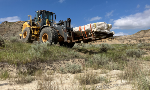The front loader taking the fossil jacket to the highway to transport to the Museum.