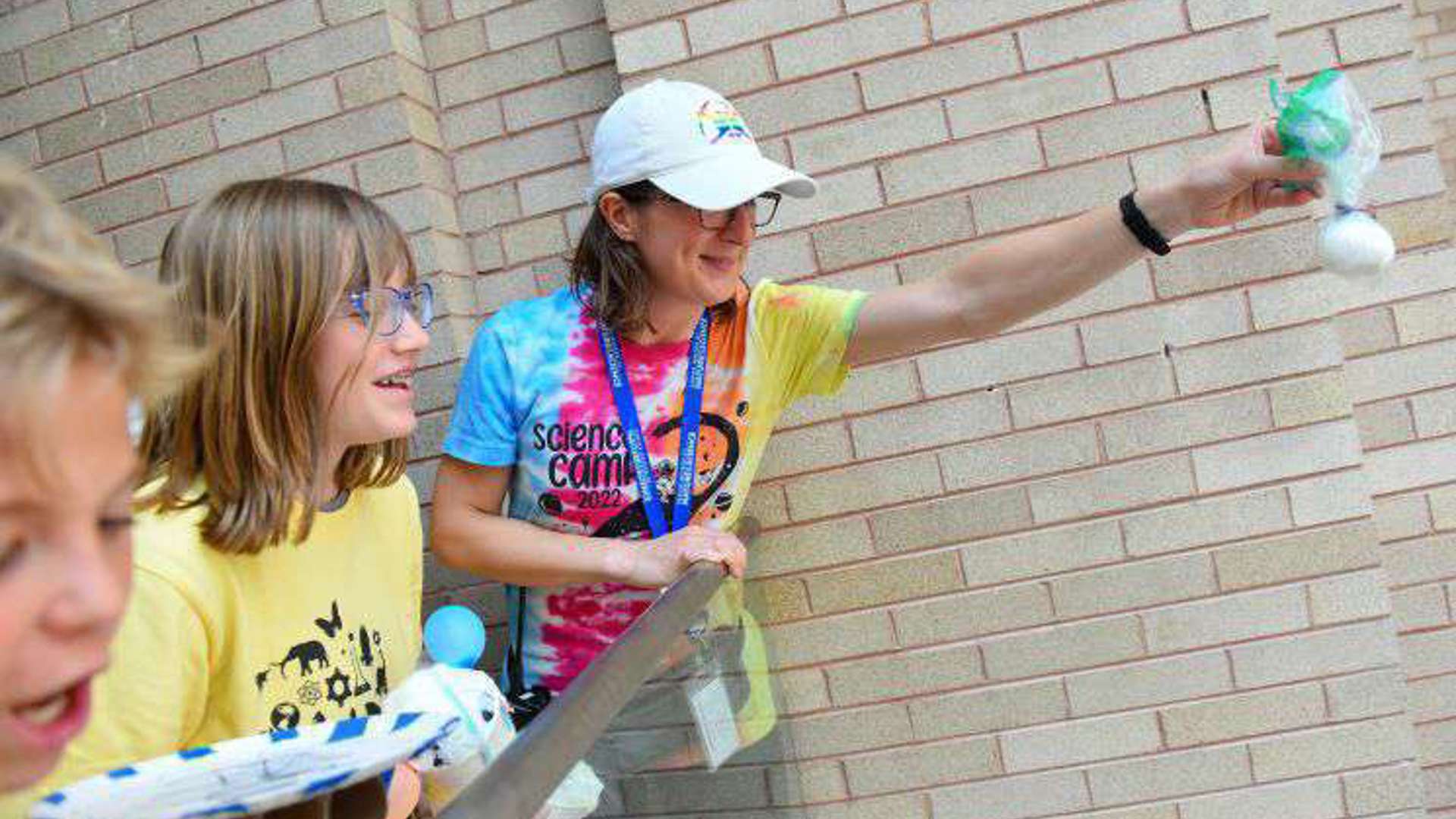 A teacher holds an egg over a landing, preparing an experiment observing the effects of gravity. 