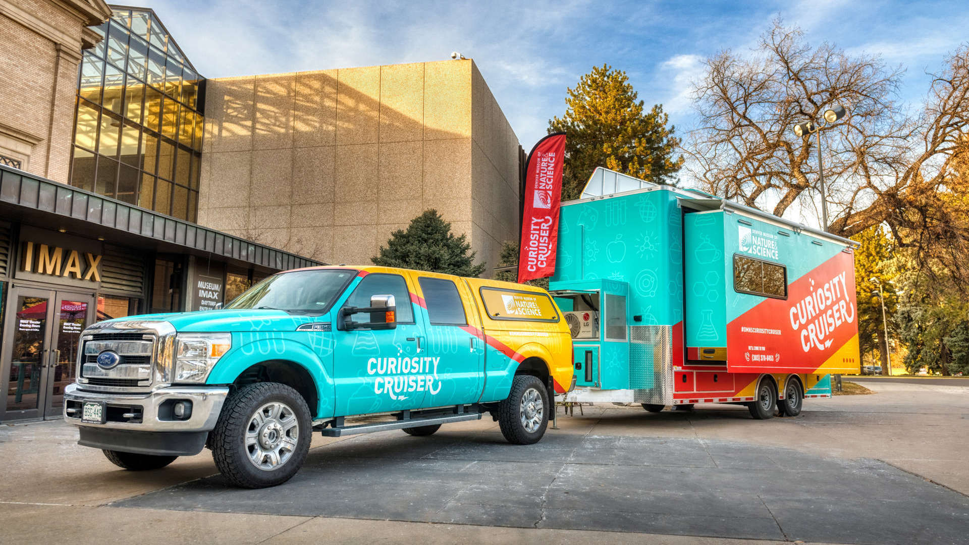 A colorful pickup truck and trailer with the Museum's Curiosity Cruiser branding