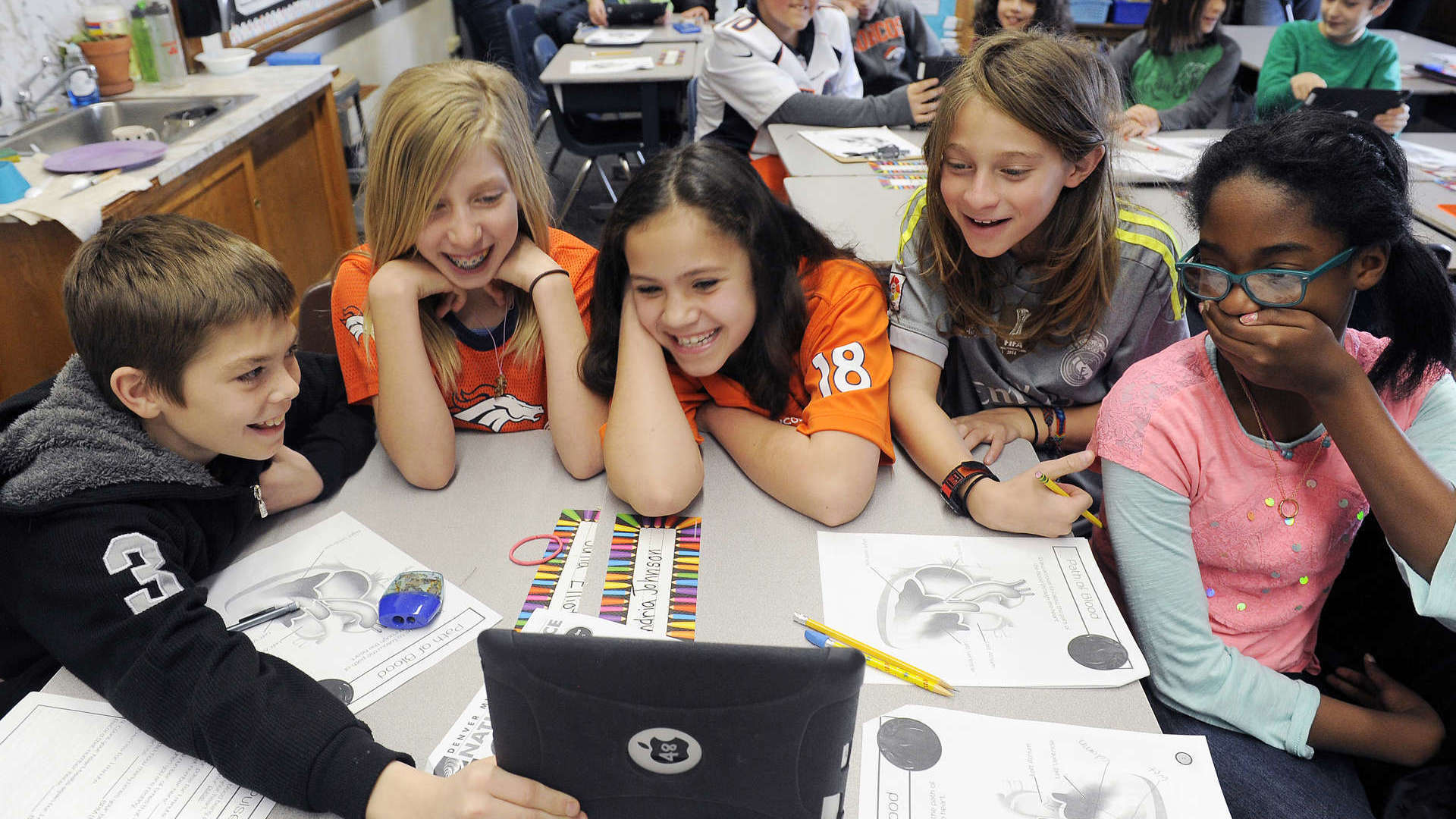 Students group around a tablet as they watch a live dissection with our "Virtual Heart" class.
