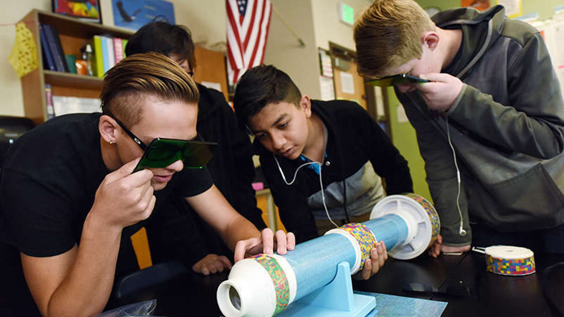 Young adults gather around a tube shaped object